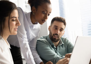 Team of engineers collaborating around a laptop
